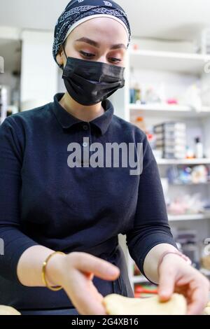 Panettiere femminile con maschera protettiva che lavora in panetteria Foto Stock