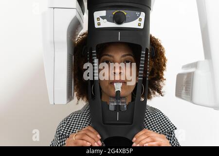Paziente femminile in piedi presso la macchina radiologica dentale in clinica Foto Stock
