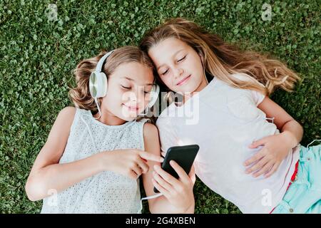 Sorridi gli amici ascoltando musica mentre si sdraiava sull'erba in estate Foto Stock