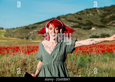 Donna dai capelli rossi che danzano sul campo di papavero Foto Stock