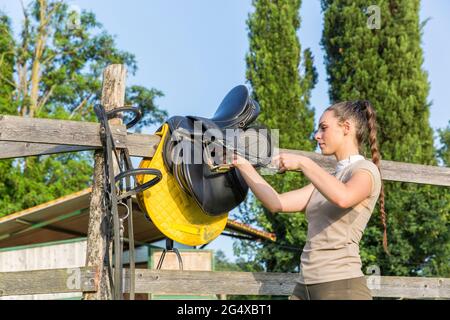 La donna la preparazione di sella sulla recinzione Foto Stock