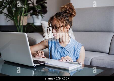 Donna d'affari che indossa occhiali che lavorano su un computer portatile a casa Foto Stock