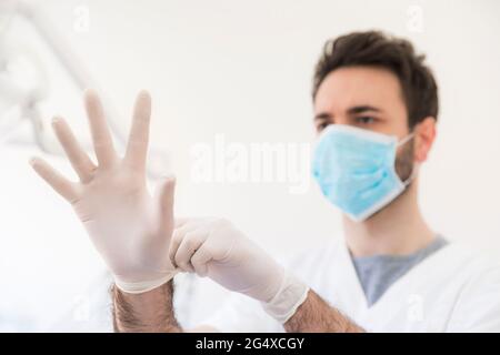 Dentista maschile indossando guanti protettivi presso la clinica medica Foto Stock