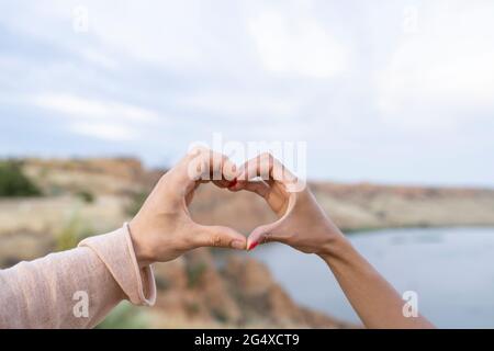 Fidanzata e fidanzata che fanno il cuore forma con le mani Foto Stock