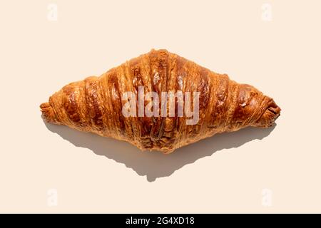 Croissant al burro appena sfornato su sfondo biege Foto Stock