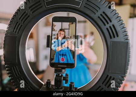 Ragazza adolescente vlogging mentre mostra i pennelli di make-up Foto Stock