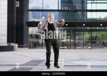 Uomo d'affari estatico in piedi su un blocco di cemento di fronte all'edificio degli uffici Foto Stock