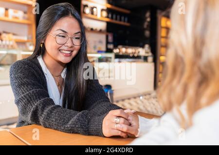 Le amiche che tengono le mani mentre si siedono al bar Foto Stock
