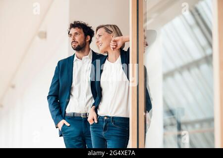 Sorridenti partner commerciali in piedi con la mano in tasca in ufficio Foto Stock