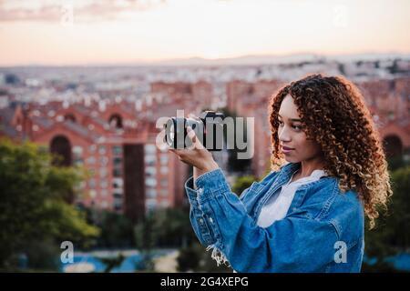 Giovane donna che fotografa attraverso la macchina fotografica per città Foto Stock