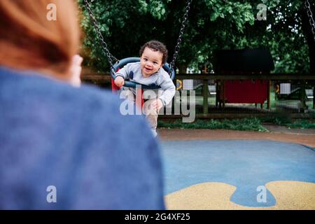 Ragazzo che dondola nel parco giochi Foto Stock