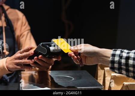 Cliente femminile che dà la carta di credito al proprietario al supermercato Foto Stock