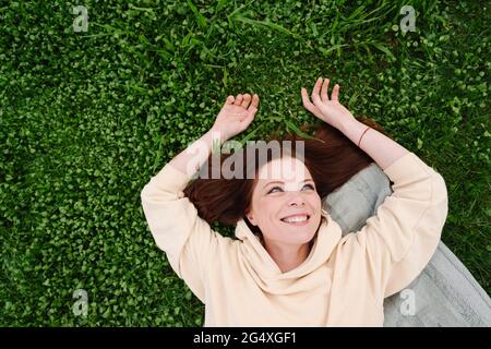 Felice donna matura che giace sull'erba al parco pubblico Foto Stock