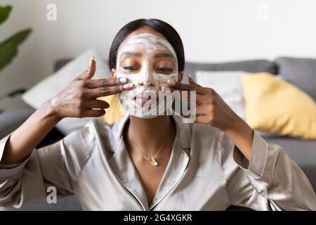 Giovane donna di applicare la maschera per il viso Foto Stock