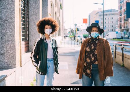 Gli amici indossano maschere protettive in piedi con distanza sociale sul sentiero Foto Stock