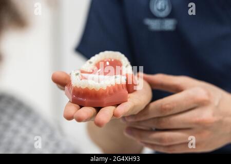 Dentista femminile maturo che mostra le dentature al paziente in clinica Foto Stock