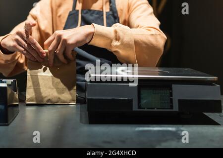 Donna che imballa il cibo in sacchetto di carta al banco del negozio Foto Stock