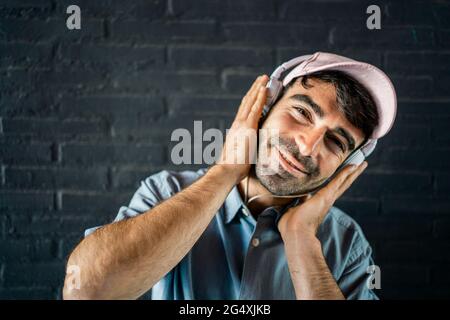 Un giovane sorridente che indossa le cuffie davanti alla parete Foto Stock
