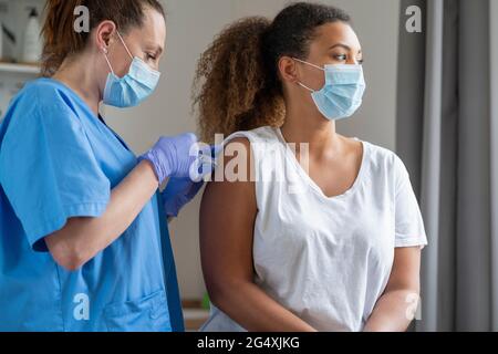 Donna con capelli ricci e maschera facciale vaccinata in ospedale Foto Stock