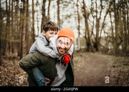 Padre dando piggyback ride al figlio nella foresta Foto Stock