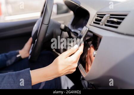 Donna che usa lo smartphone durante la guida dell'auto Foto Stock