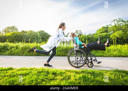 Donna anziana in sedia a rotelle godendosi con custode nel parco Foto Stock