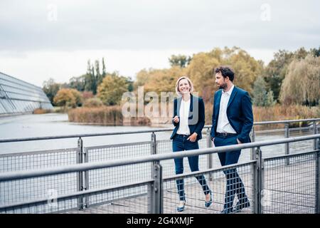 Imprenditori maschili e femminili sorridono mentre camminano sul ponte Foto Stock