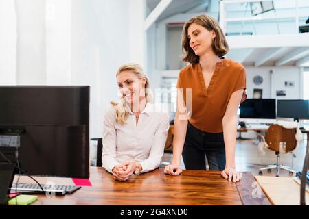 Imprenditrici che guardano al computer mentre lavorano insieme in ufficio creativo Foto Stock
