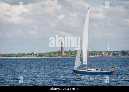 Germania, Schleswig-Holstein, Laboe, Lone vela lungo Kiel Fjord con Laboe Naval Memorial in background Foto Stock