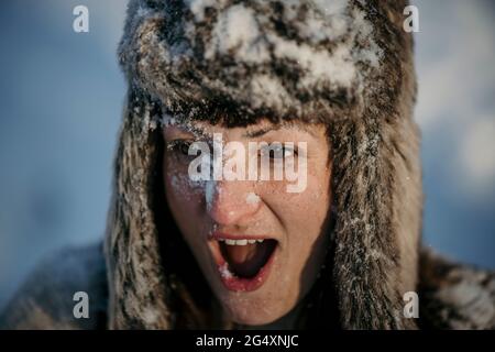 Donna sorpresa che indossa cappello cacciatori guardando via con la bocca aperta Foto Stock