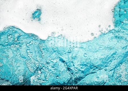 Schiuma bianca blu chiaro fondo acqua closeup, mare oceano schiuma bordo onda, schiuma schiuma forma bolle, sfondo laccio, sapone modello suds, superficie saponata Foto Stock