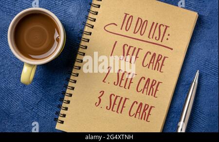 elenco di cose da fare - cura di sé, scrittura a mano in un notebook a spirale con una tazza di caffè, mentale, emotivo, e concetto di salute fisica Foto Stock