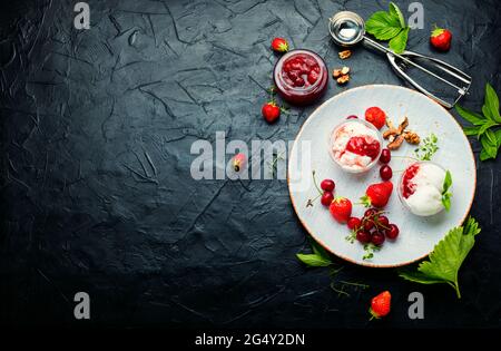 Dessert estivo, gelato con fragole e ciliegie. Gelato con marmellata di frutti di bosco. Spazio fotocopie Foto Stock