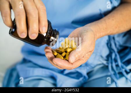 Medico asiatico che tiene e versa e tiene pillole di vitamina C medicina dal flacone al paziente per il trattamento di infezione in ospedale; farmacia farmacia con Foto Stock