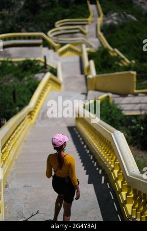 Una giovane donna thailandese cammina lungo la scala vicino al tempio buddisti Foto Stock