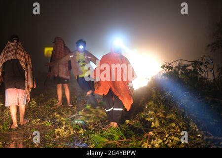 Un volontario sta rimuovendo un blocco di alberi caduti dopo la tempesta su una strada distante in un altopiano della Thailandia settentrionale, alla sera del 4 giugno 2021 Foto Stock