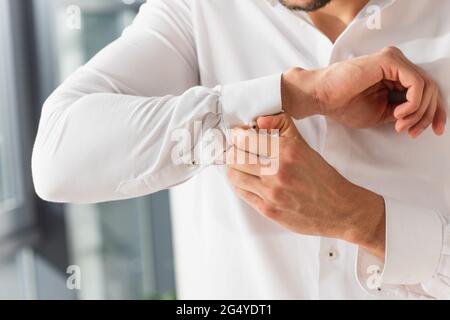 Vista tagliata dell'uomo che fa da bottonare la manica di camicia Foto Stock