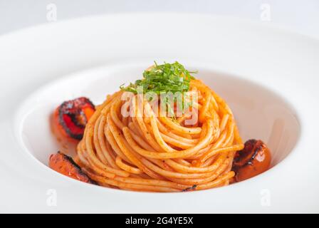 Ciotola di Spaghetti con pomodori ciliegini e basilico grattugiato Foto Stock