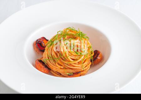 Ciotola di Spaghetti con pomodori ciliegini e basilico grattugiato Foto Stock