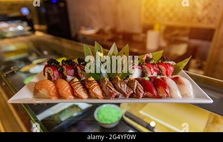 Vari sushi su piatti bianchi al banco del ristorante sushi Foto Stock