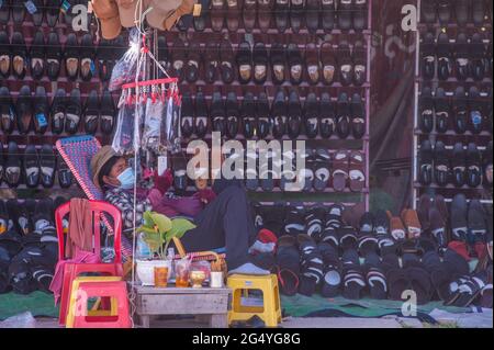 Phnom Penh, Cambogia. 24 giugno 2021. Per 4 mesi Phnom Penh ha combattuto contro un picco COVID - 19. Un fornitore di scarpe, che indossa una maschera protettiva / copertura, attende i clienti durante la pandemia del coronavirus. Credit: Kraig Lieb / Alamy Live News Foto Stock