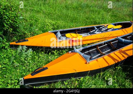 Due kayak arancioni sulla riva dell'erba in una giornata di sole Foto Stock