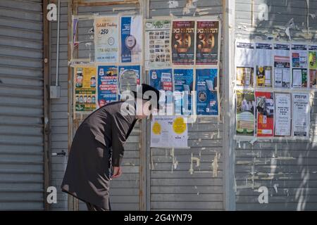 Un giovane ebreo ortodosso, probabilmente un Satmar, guarda i poster pubblicitari che sono per lo più in Yiddish. Su Lee Ave. A Williamsburg, Brooklyn, New York. Foto Stock