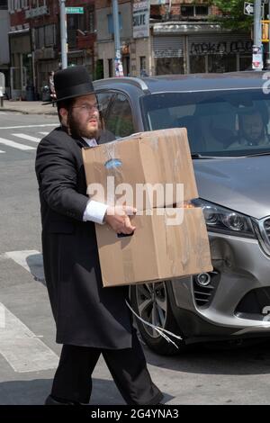 Un ebreo ortodosso prende i pacchetti degli articoli estivi del suo fratello per essere bused al campo che parteciperanno. A Williamsburg, Brooklyn, New York ci Foto Stock