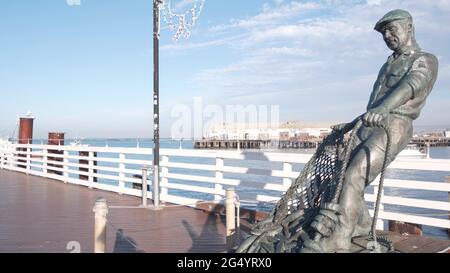 Monterey, California USA -9 dicembre 2020 Old Fisherman Wharf vicino Cannery Row. Uomo operaio figura, pesce in rete, statua di bronzo di Jesse Corsaut, monumento sc Foto Stock