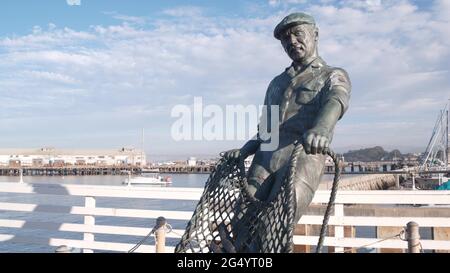 Monterey, California USA -9 dicembre 2020 Old Fisherman Wharf vicino Cannery Row. Uomo operaio figura, pesce in rete, statua di bronzo di Jesse Corsaut, monumento sc Foto Stock