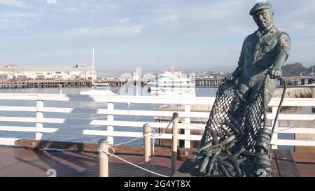 Monterey, California USA -9 dicembre 2020 Old Fisherman Wharf vicino Cannery Row. Uomo operaio figura, pesce in rete, statua di bronzo di Jesse Corsaut, monumento sc Foto Stock