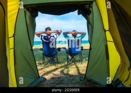 coppia uomo e donna rilassante vicino campeggio tenda sul mare Foto Stock