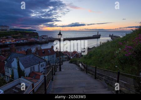 199 scalini che conducono dall'abbazia fino al porto di Whitby. Colori caldi nel cielo al tramonto. Destinazione turistica dello Yorkshire Foto Stock