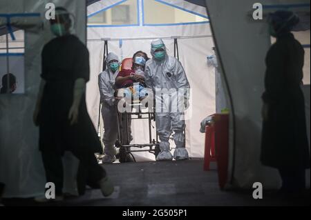 Giacarta, Indonesia. 24 Giugno 2021. Gli operatori sanitari che indossano tute protettive portano un paziente COVID-19 in un ricovero temporaneo in un ospedale di Giacarta, Indonesia, 24 giugno 2021. Credit: Agung Kuncahya B./Xinhua/Alamy Live News Foto Stock